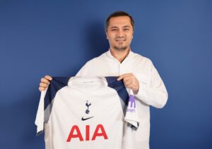 Bild zeigt, wie Dr. Abdulaziz Balwi ein Trikot des Premiere League Klubs Tottenham Hotspur in beiden Händen hält